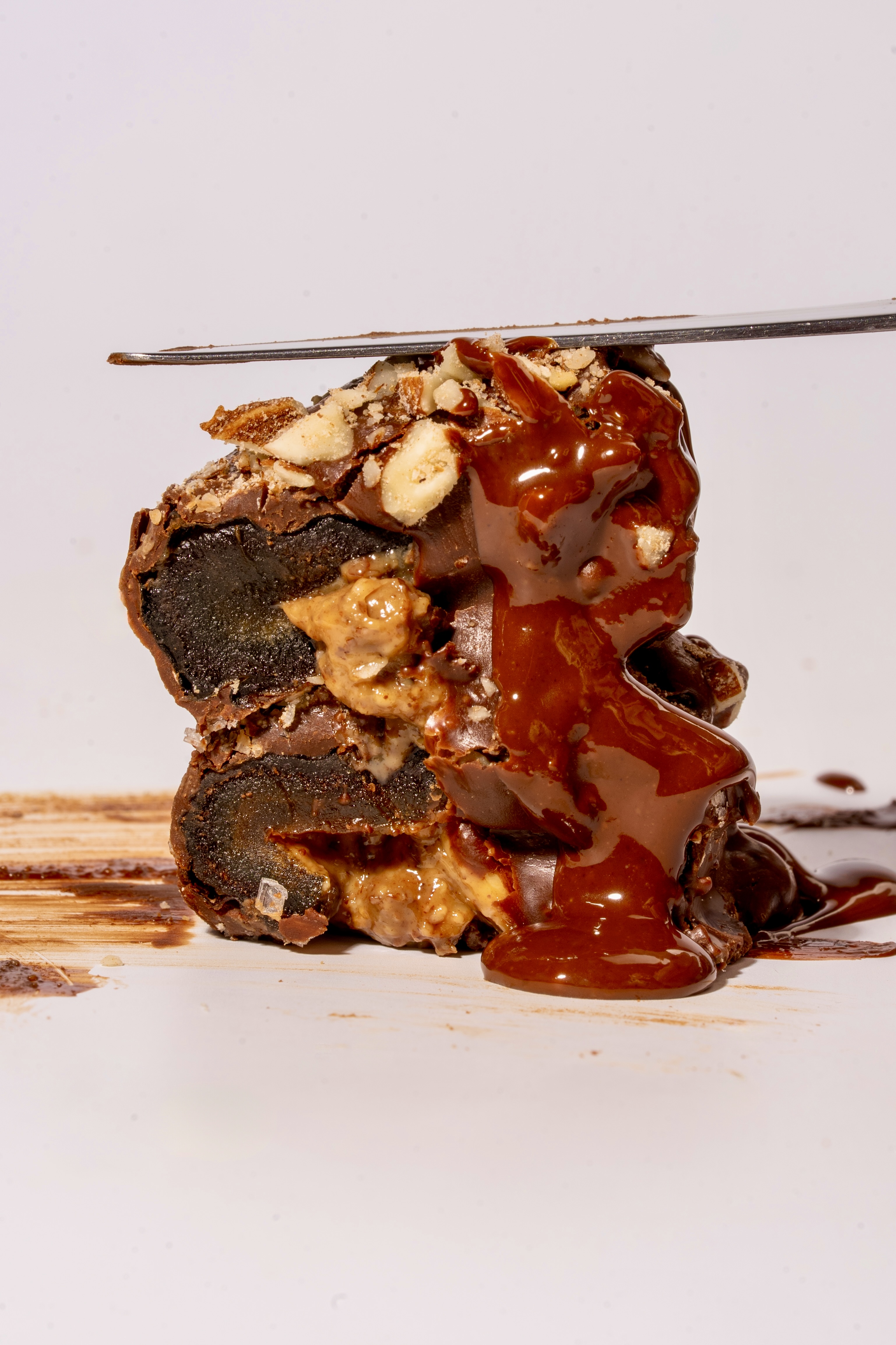 MessyDate cut open with a knife revealing layers of date, nut butter and chocolate